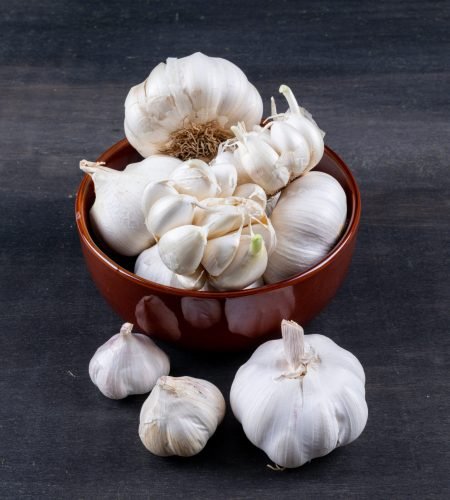 high angle view bunches of garlic in bowl on dark wooden background. horizontal